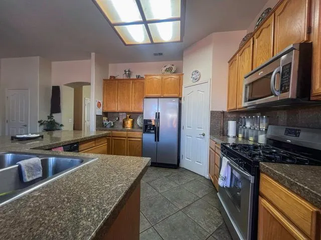 a kitchen with stainless steel appliances granite countertop a stove a sink a refrigerator and a microwave