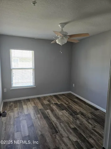 an empty room with a window and a ceiling fan