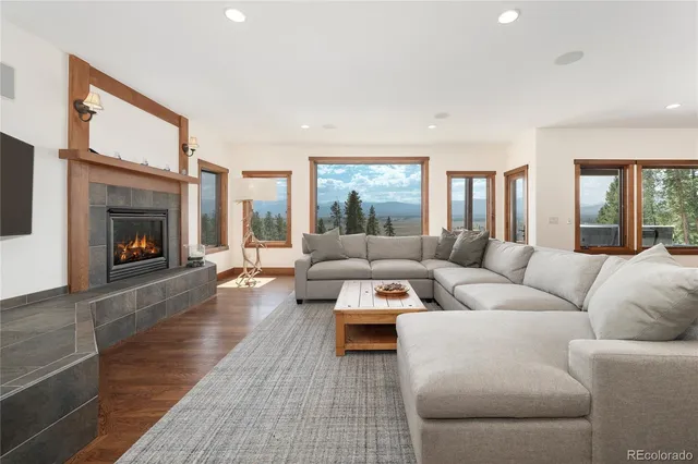 a living room with furniture kitchen view and a wooden floor