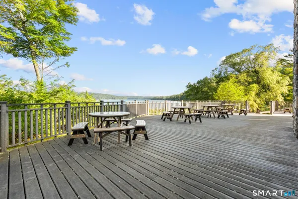 a roof deck with table and chairs a barbeque with wooden floor and fence