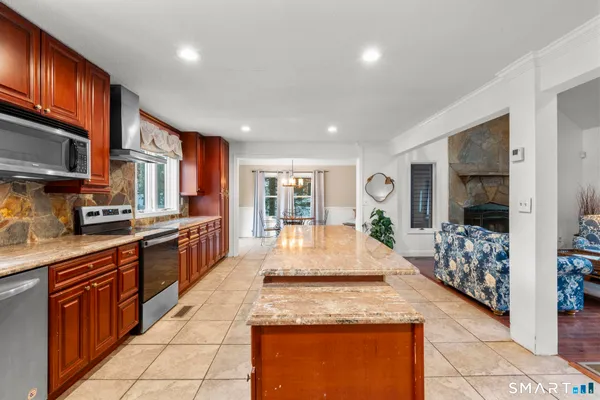 a large kitchen with granite countertop a large counter top stainless steel appliances a stove a sink and cabinets