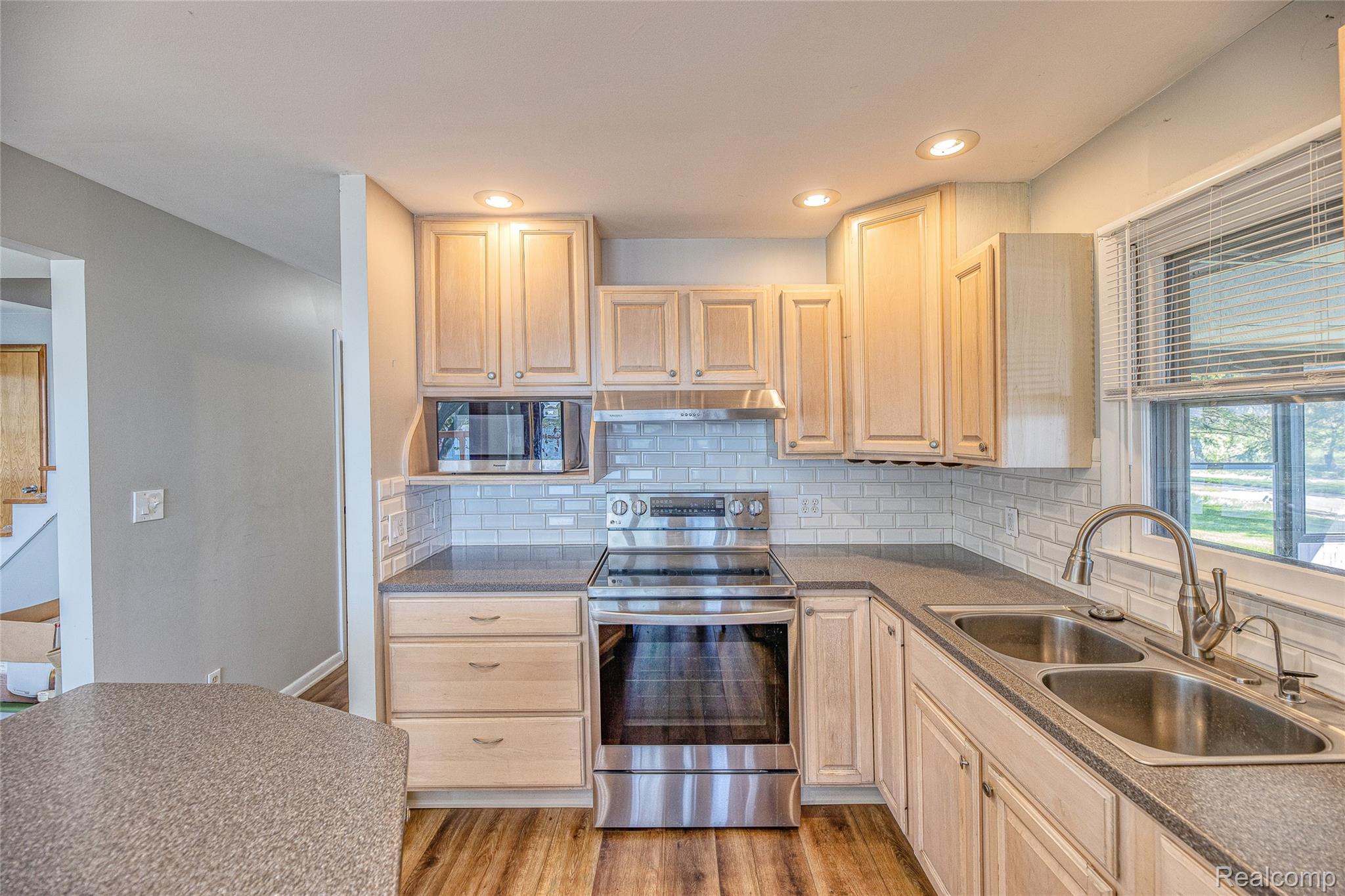 2855 Farmers Creek Road Metamora, MI 48455 - Photo 10 of 51 Kitchen featuring wood-finish flooring, light wood cabinetry, stainless steel appliances, and a subway tile backsplash