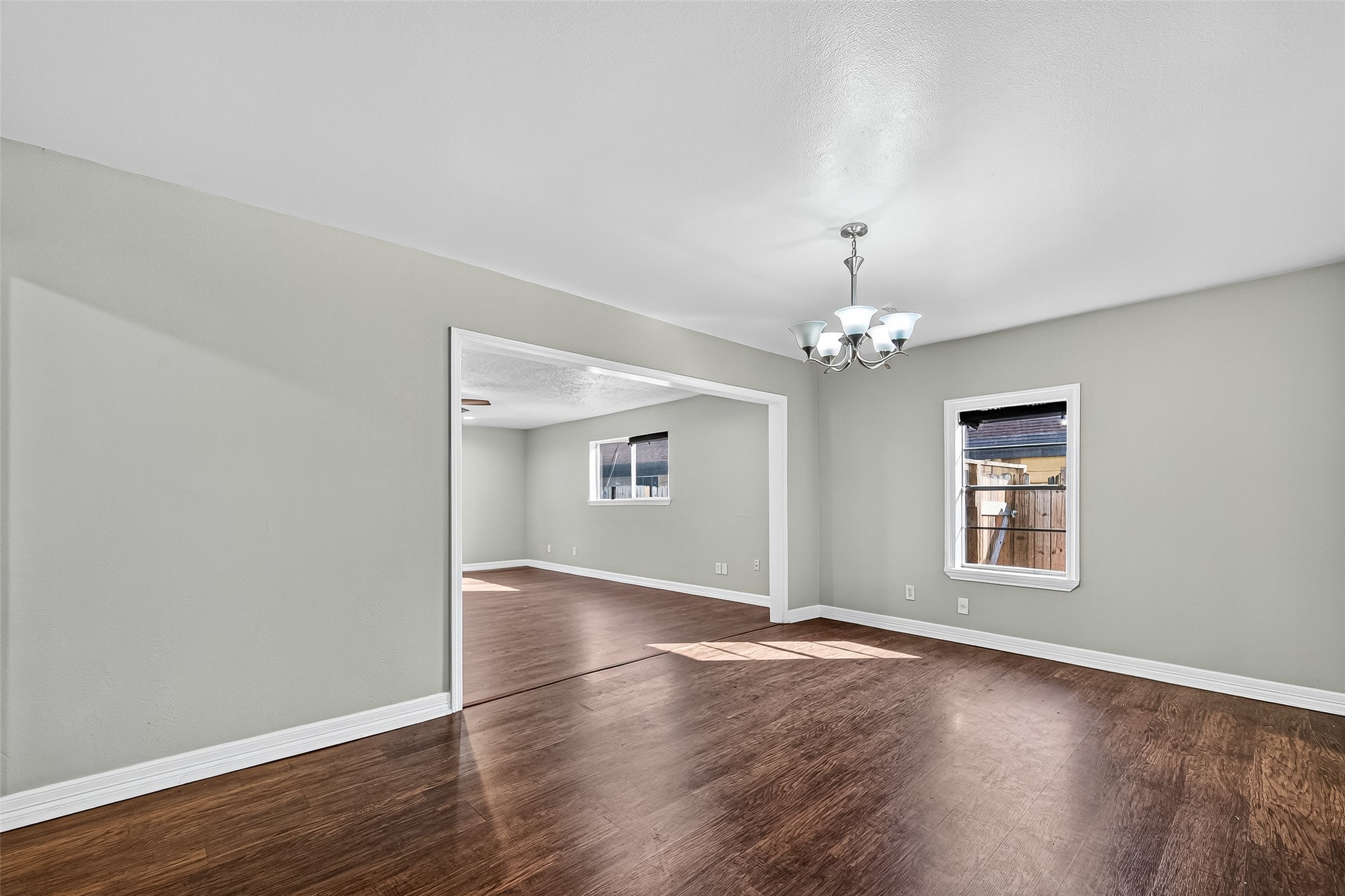 4034 Caplin Street Houston, TX 77026 - Photo 13 of 37 an empty room with wooden floor chandelier and windows