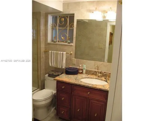 a bathroom with a granite countertop toilet sink and mirror