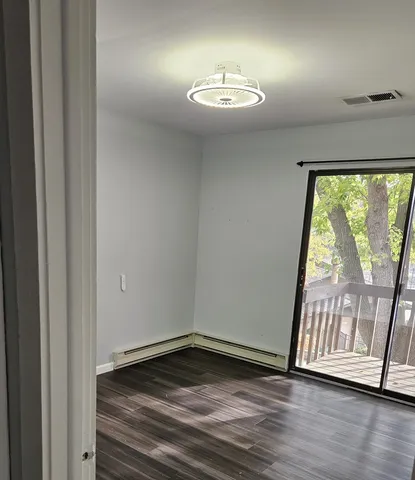 a view of an empty room with wooden floor and a window
