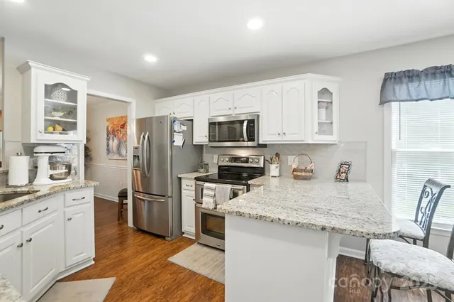 a kitchen with granite countertop a refrigerator stove microwave and sink