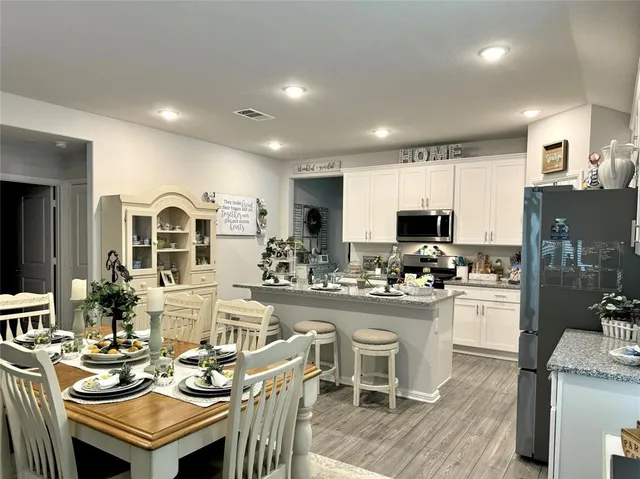 a kitchen with sink refrigerator dining table and chairs