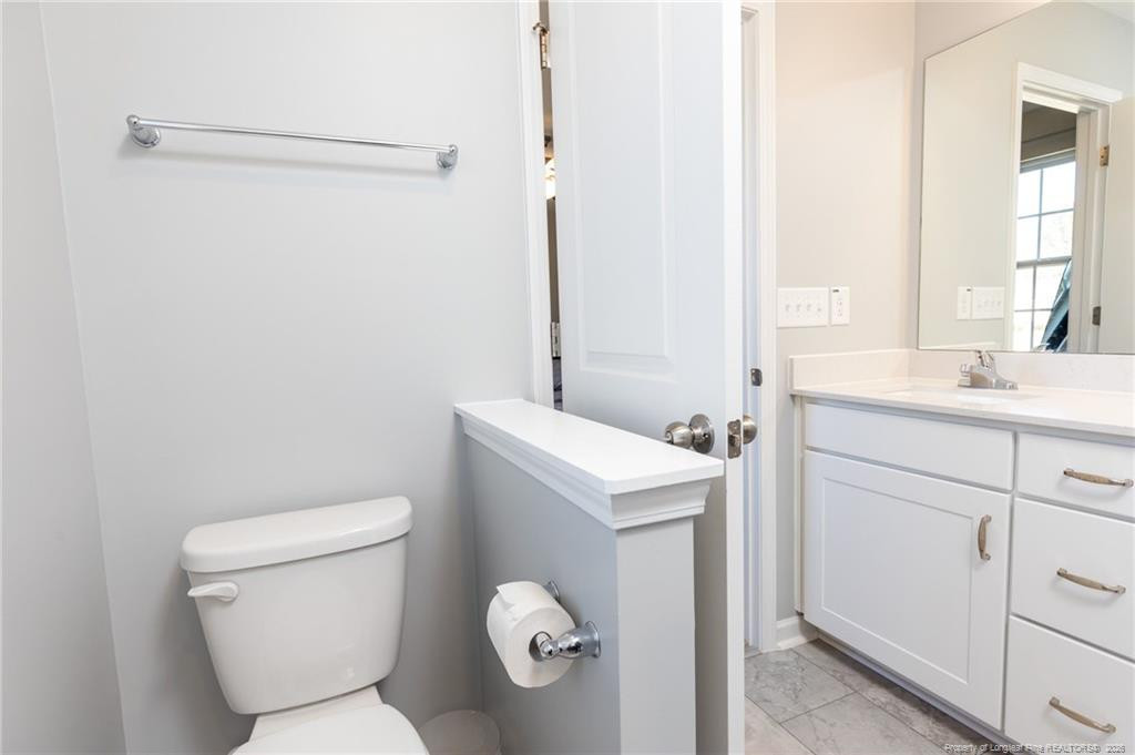 325 Ray Byrd Road Lillington, NC 27546 - Photo 22 of 26 a bathroom with a toilet sink vanity and mirror