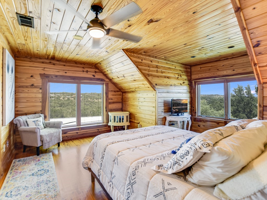 254 Middleton Road Spicewood, TX 78669 - Photo 20 of 32 a bedroom with a bed and large windows