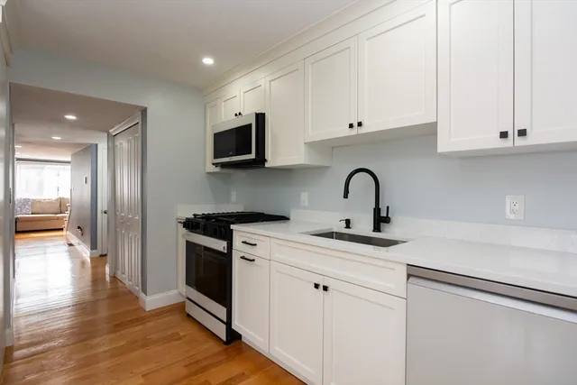 a kitchen with white cabinets stainless steel appliances and sink