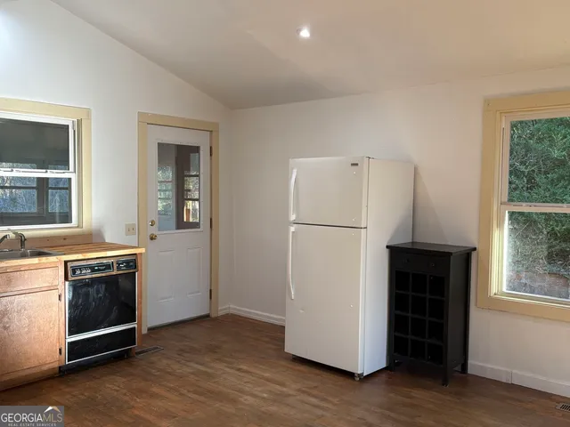 a view of a kitchen with a sink a refrigerator and wooden floor