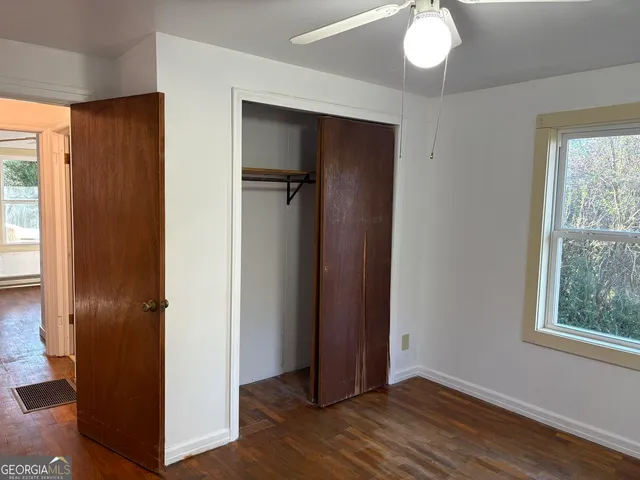 an empty room with wooden floor cabinet and windows