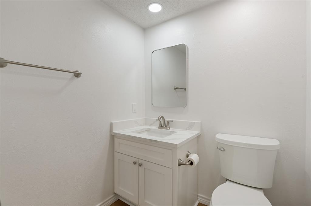 5300 Keller Springs Road, Unit 2042 Dallas, TX 75248 - Photo 13 of 28 Powder bathroom vanity with white cabinetry, a marble-patterned countertop, and an undermount sink