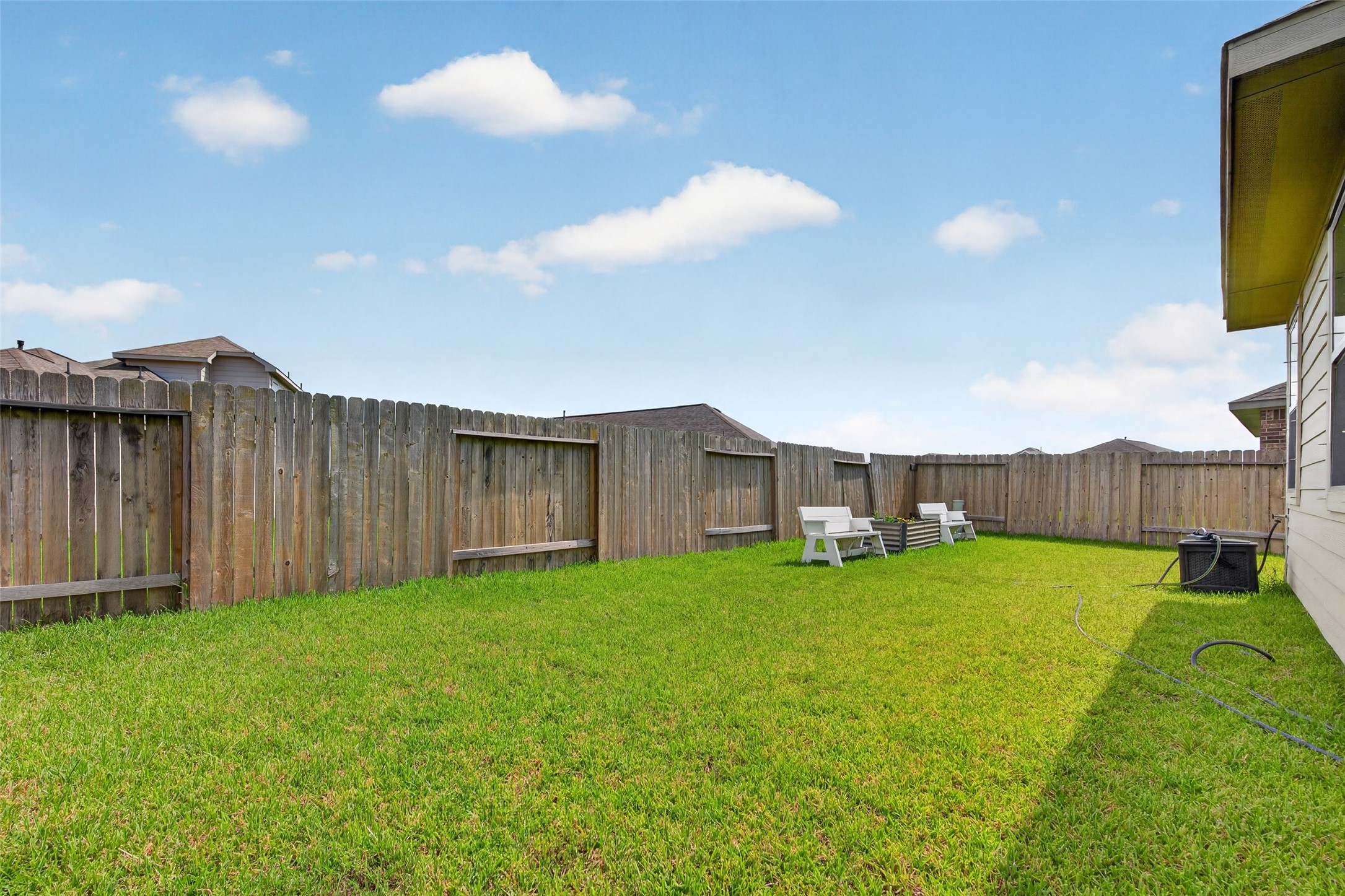 1329 Red Hills Drive Rosharon, TX 77583 - Photo 27 of 27 This photo showcases a spacious, fenced backyard with well-maintained grass and a few outdoor chairs, providing a private and inviting space for relaxation or entertaining.
