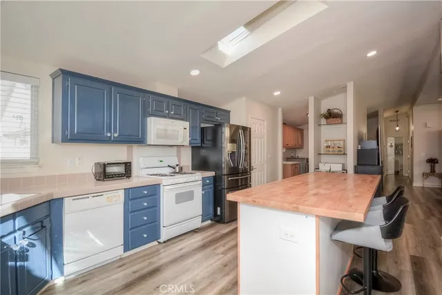 a kitchen with stainless steel appliances kitchen island granite countertop a table chairs sink refrigerator and cabinets