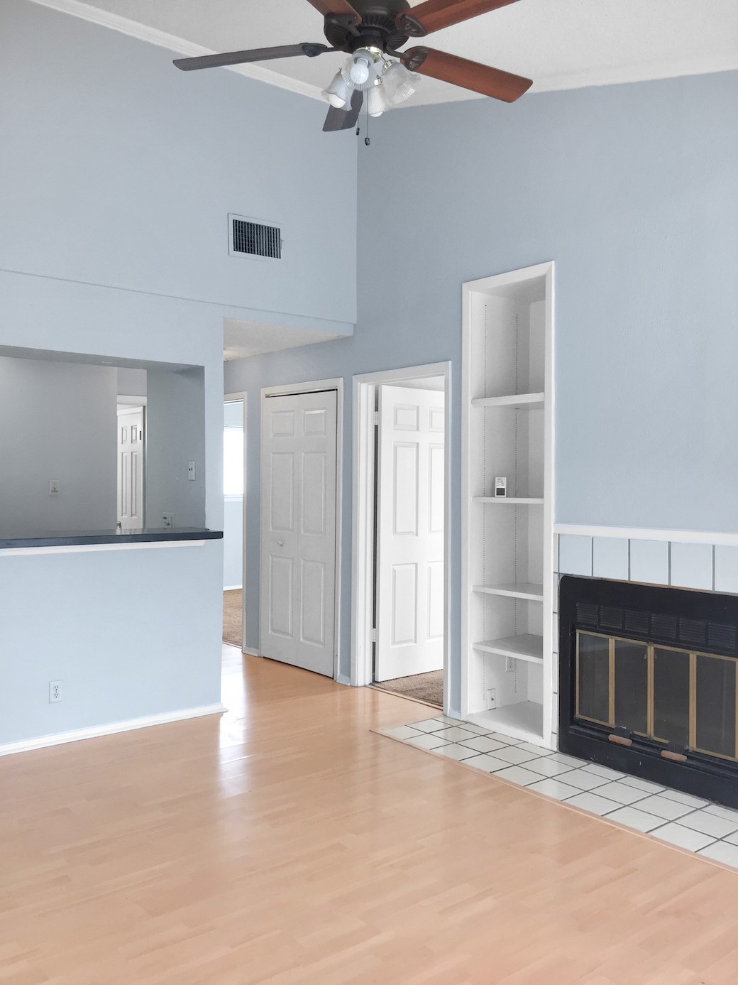 807 West 25th Street, Unit 312 Austin, TX 78705 - Photo 4 of 15 Unfurnished living room featuring light wood-style floors, a high ceiling, ceiling fan, a fireplace, and built in features