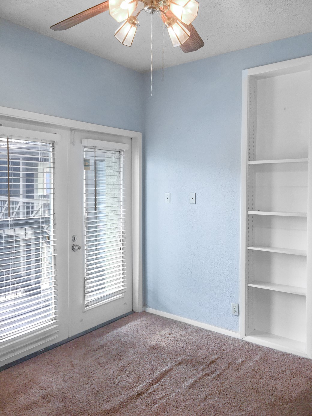 807 West 25th Street, Unit 312 Austin, TX 78705 - Photo 9 of 15 Carpeted spare room featuring a ceiling fan, french doors, a textured ceiling, and built in shelves