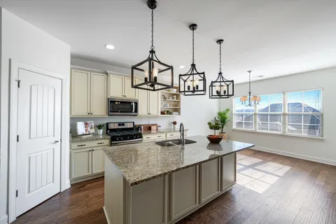 a kitchen with stainless steel appliances granite countertop a sink a stove and a wooden floor