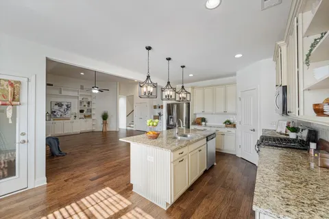 a large kitchen with kitchen island a stove a sink dishwasher and a dining table with wooden floor