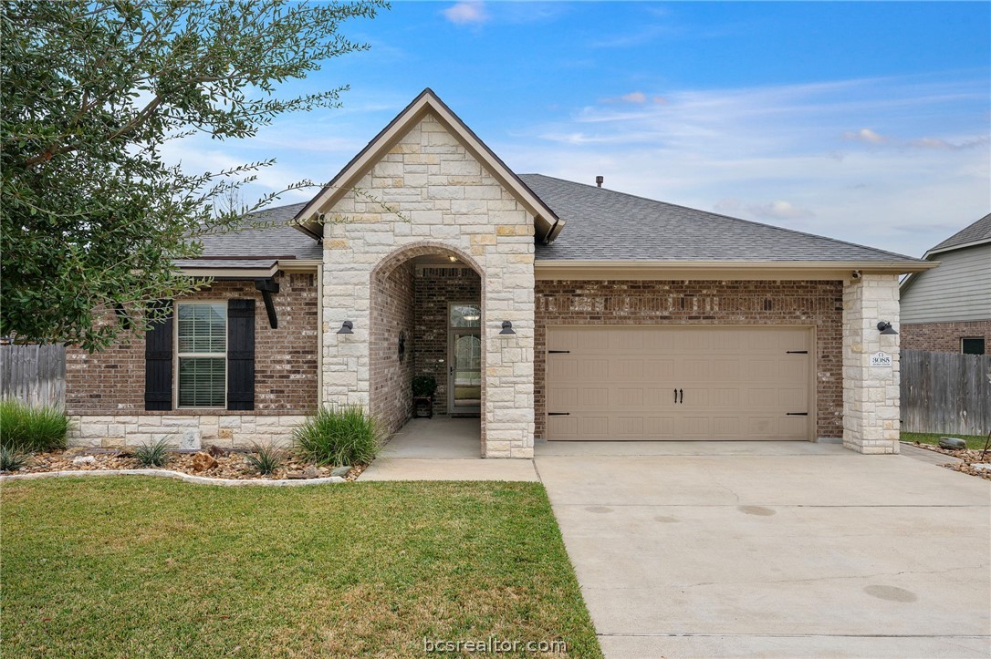 3085 Archer Circle Bryan, TX 77808 - Photo 1 of 32 View of front of house with brick siding, a shingled roof, an attached garage, driveway, and stone accents.
