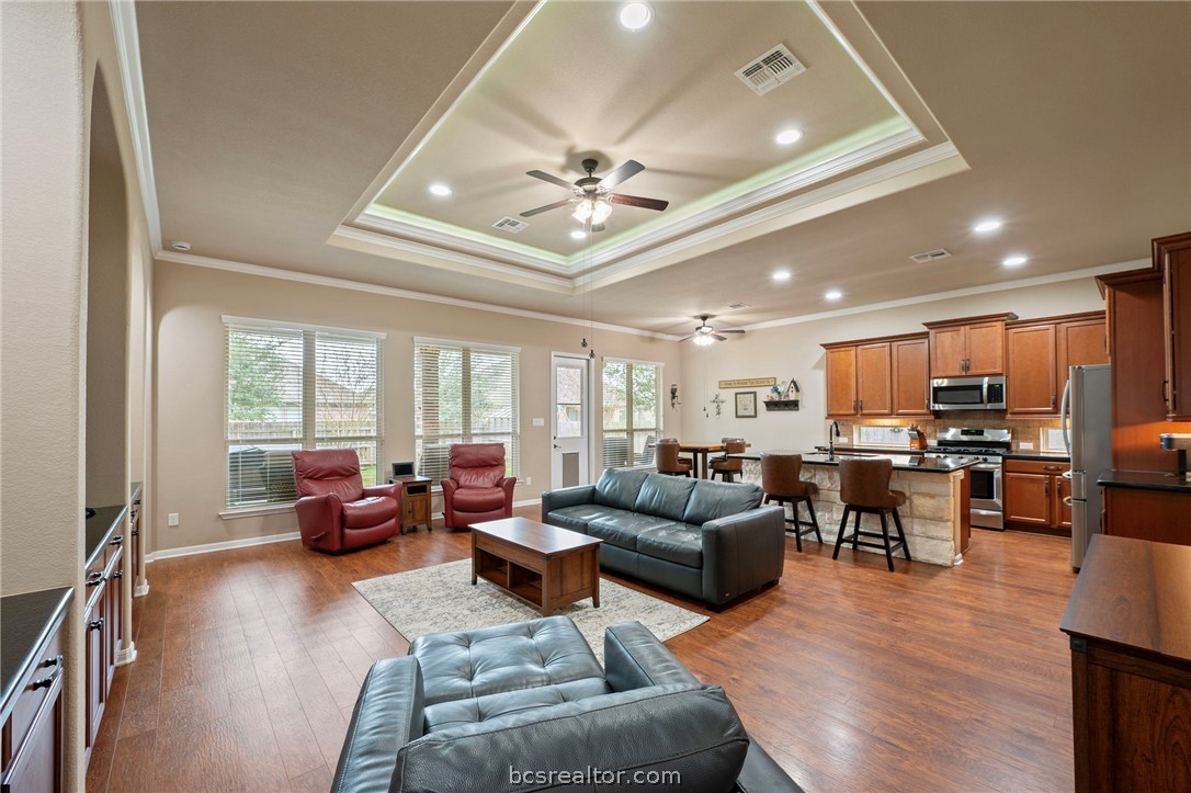 3085 Archer Circle Bryan, TX 77808 - Photo 4 of 32 Living room featuring a raised ceiling, wood flooring, ceiling fan, ornamental molding, and healthy amount of natural light