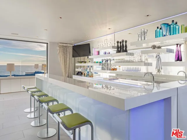 a living room with couches and a flat screen tv with kitchen view