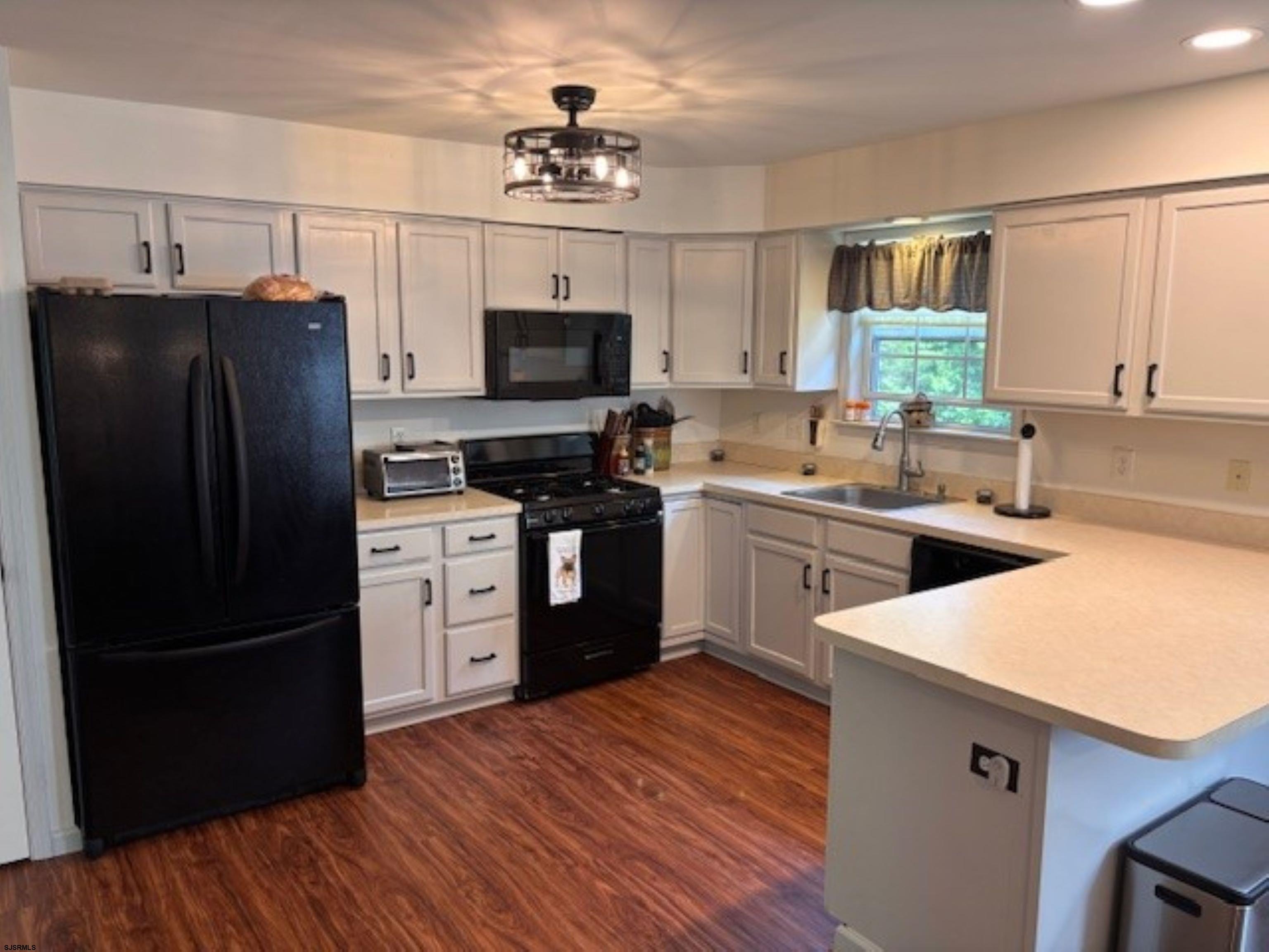 120 Head Of River Road Corbin City, NJ 08270 - Photo 3 of 19 a kitchen with a refrigerator a sink dishwasher and a stove with wooden floor