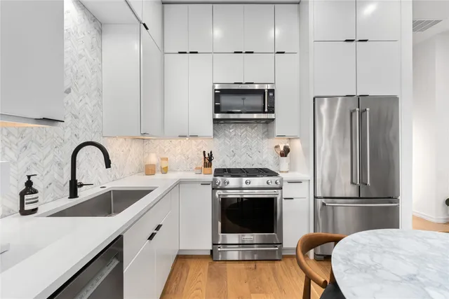 a kitchen with stainless steel appliances a stove refrigerator sink and microwave