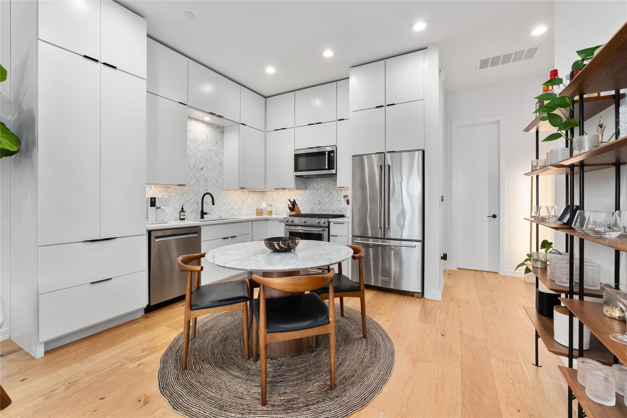 410 West Alpine Road, Unit 10 Austin, TX 78704 - Photo 9 of 31 a kitchen with stainless steel appliances a refrigerator a stove a sink and a dining table with wooden floor