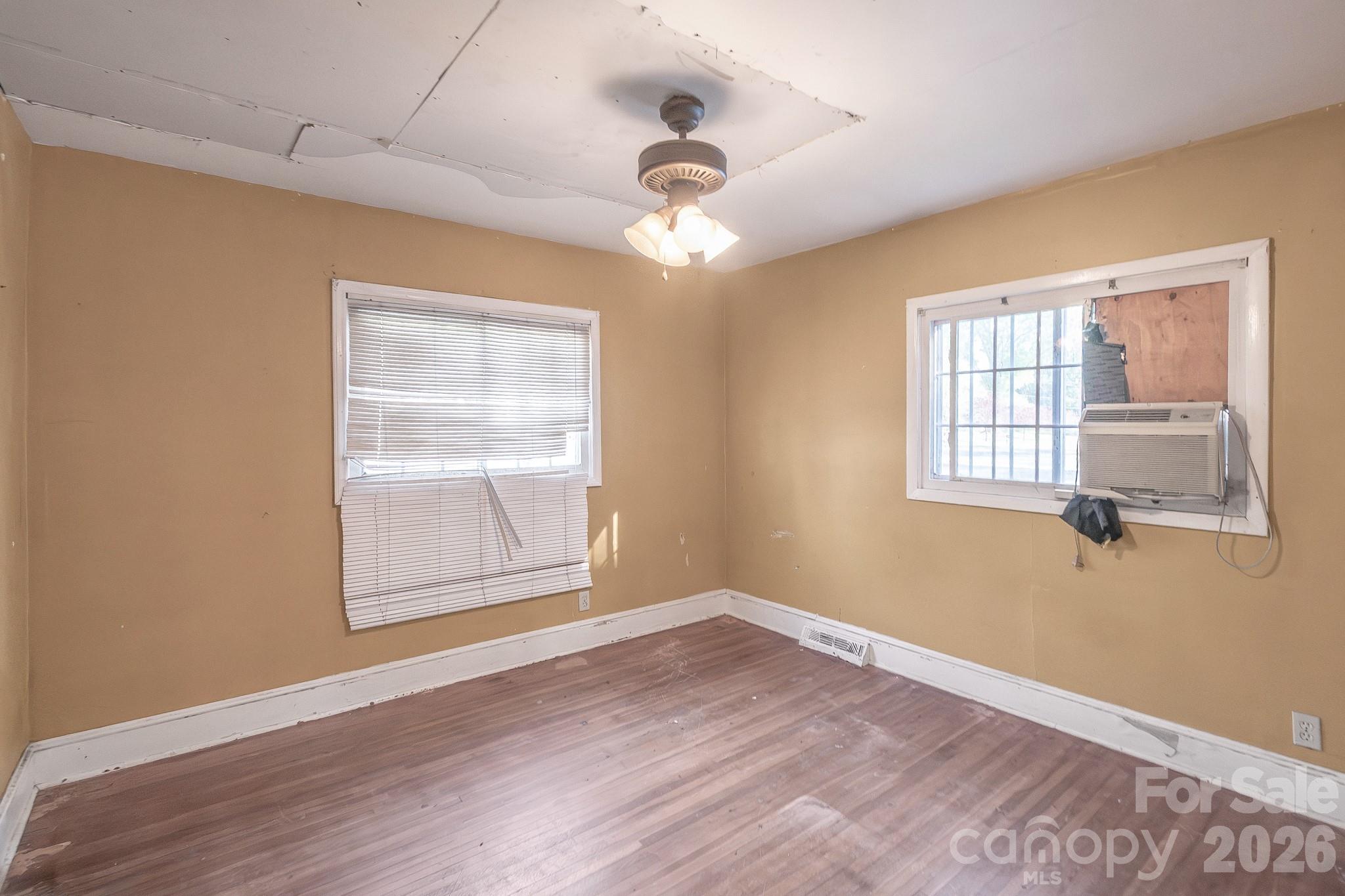 4430 West Tyvola Road Charlotte, NC 28208 - Photo 19 of 33 an empty room with wooden floor chandelier fan and windows