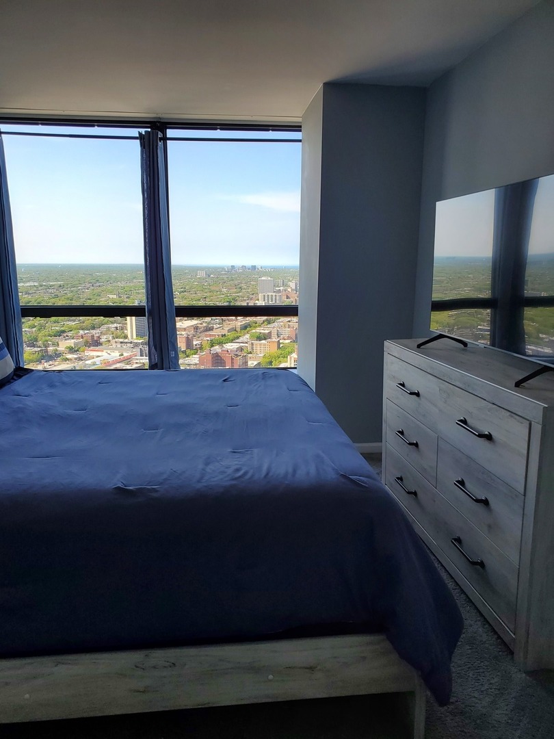5415 North Sheridan Road, Unit 4809 Chicago, IL 60640 - Photo 10 of 12 a bedroom with a bed and a flat tv screen on dresser