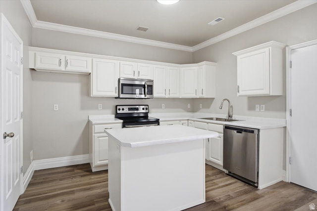 4496 West 11800 South South Jordan, UT 84009 - Photo 9 of 33 Kitchen with stainless steel appliances, white cabinets, light countertops, a kitchen island, and ornamental molding