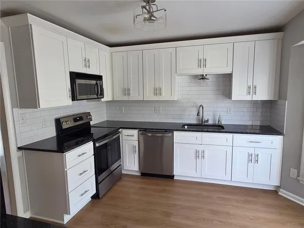 a kitchen with granite countertop white cabinets white stainless steel appliances and a sink