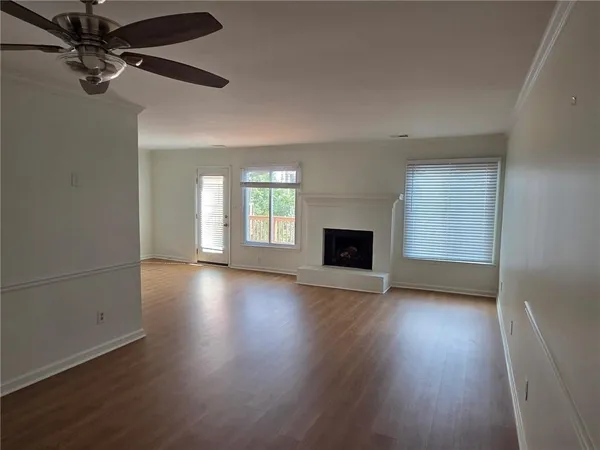 an empty room with wooden floor fireplace and windows