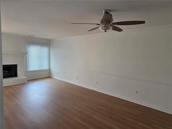 an empty room with wooden floor chandelier fan and windows