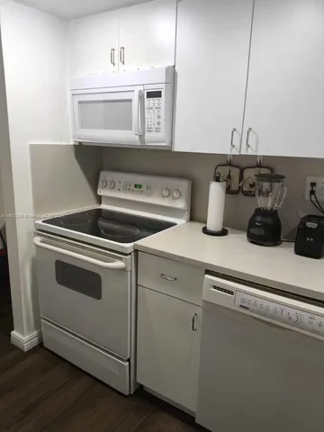 a kitchen with granite countertop white cabinets and white appliances