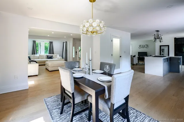 a kitchen with stainless steel appliances granite countertop a refrigerator a stove top oven a sink dishwasher and white cabinets with wooden floor