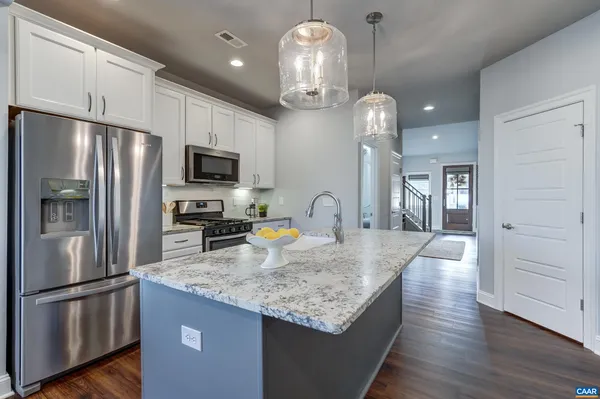 a kitchen with granite countertop a refrigerator a stove a sink cabinets and wooden floor