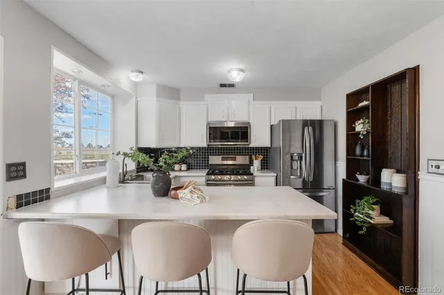 a kitchen with stainless steel appliances granite countertop a refrigerator a stove a sink a dining table and chairs