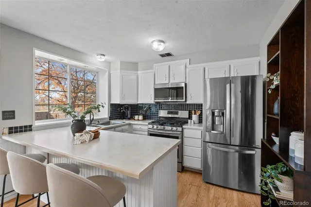 a kitchen with a refrigerator a stove a sink dishwasher and white cabinets with wooden floor