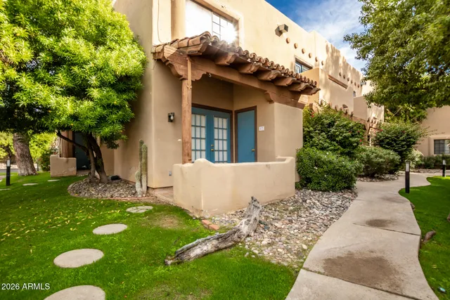 a view of a white house with a yard and table and chair under large trees