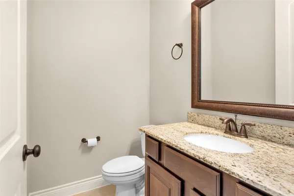 a bathroom with a granite countertop sink and a toilet