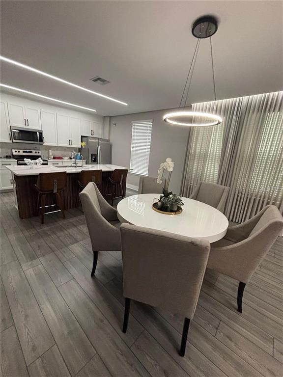 4812 Lime Rickey Alley Winter Garden, FL 34787 - Photo 5 of 19 a kitchen with a table chairs a sink dishwasher window and cabinets