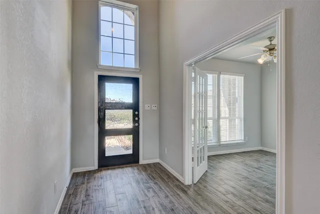 an empty room with wooden floor closet and windows