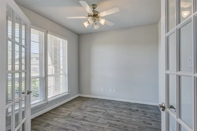 a view of an empty room with window and wooden floor