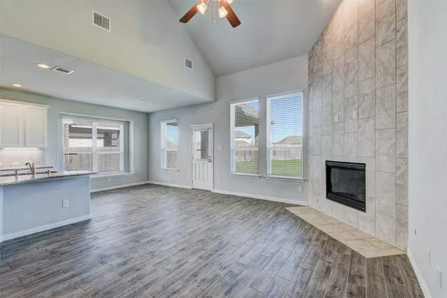 an empty room with windows fireplace and wooden floor