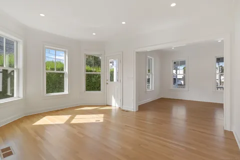 a view of an empty room with window and wooden floor