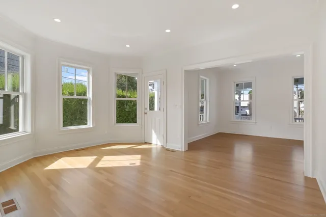 a view of an empty room with window and wooden floor