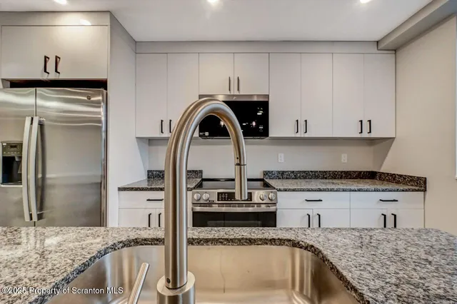 a kitchen with granite countertop a sink stainless steel appliances and cabinets