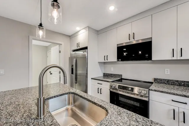 a kitchen with stainless steel appliances granite countertop a sink a stove a refrigerator cabinets and a dining table